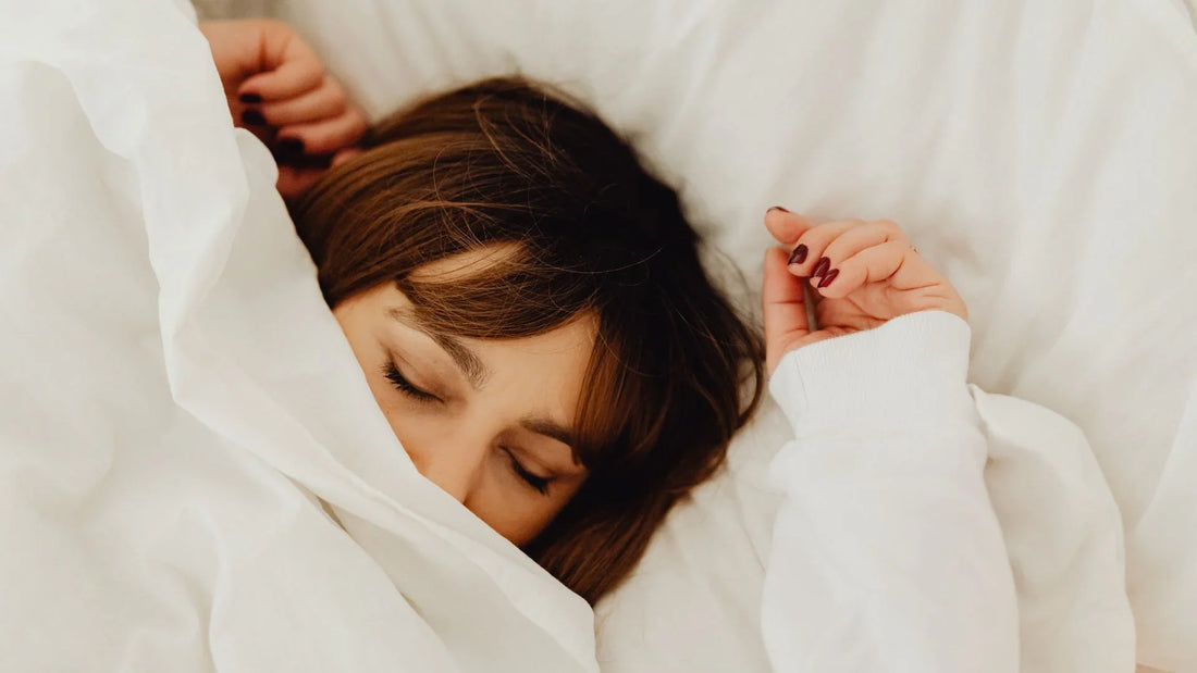 Femme couchée dans son lit. La couverture couvre la moitié de son visage. 
